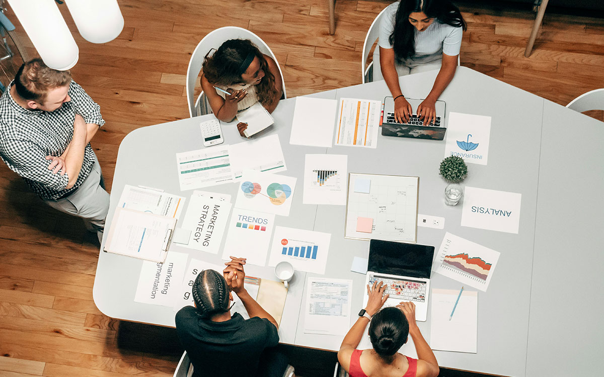 Top down view of Gelos employees working in collaboration together at a large desk